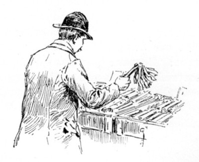 man dusting spines of books in boxes on a table