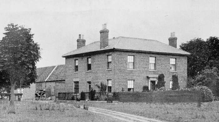 Exterior view of a substantial brick countryside manor with three fireplaces.