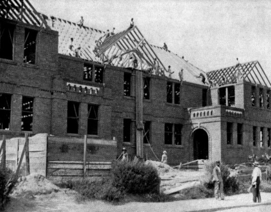 THE OFFICE BUILDING IN PROCESS OF ERECTION.

Student carpenters shown at work.