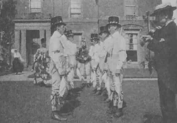 THE BIDFORD MORRIS SIDE.<br />  (FIDDLER in foreground, to the right; HOBBY-HORSE—left, and FOOL—centre, beyond Dancers.)