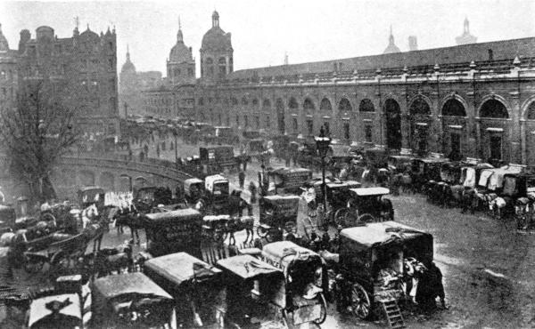 DELIVERING MEAT AT SMITHFIELD TODAY  There is an inclined road by the tree in the center of the picture, leading to the special railroad freight depot. Cars are also run directly under the market and their cargoes are delivered by hydraulic lifts to the stands above.