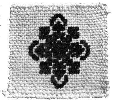 A square of silk canvas with cross-stitched pattern of chenille