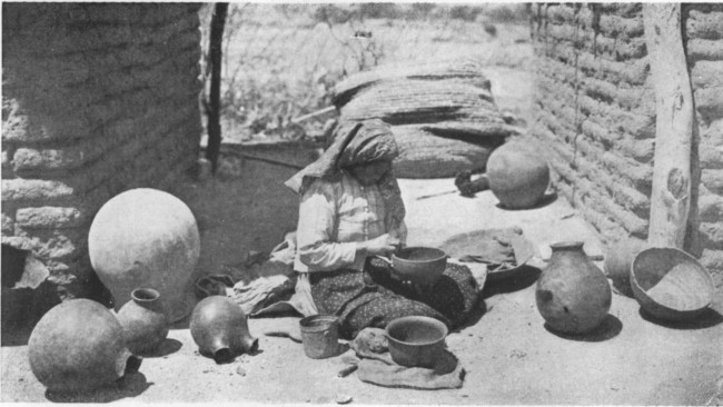 In the bright Arizona sunshine before their little square adobe houses Indian women are fashioning pottery into curious shapes