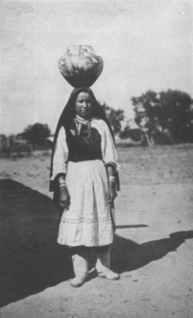 An Indian girl of Isleta, New Mexico, carrying a water jar.