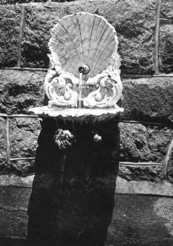 THIS WALL FOUNTAIN WITH ITS SHELL BACKGROUND AND BASIN IS MOST FITTINGLY PLACED