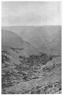 Fig. 29—Cotahuasi on the floor of the Cotahuasi canyon. The even skyline of the background is on a rather even-topped lava plateau. The terrace on the left of the town is formed on limestone, which is overlain by lava flows. A thick deposit of terraced alluvium may be seen on the valley floor, and it is on one of the lower terraces that the city of Cotahuasi stands. The higher terraces are in many cases too dry for cultivation. The canyon is nearly 7,000 feet (2,130 m.) deep and has been cut through one hundred principal lava flows.