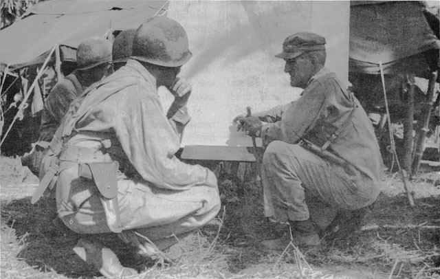 MAJ. GEN. JOHN R. HODGE, XXIV Corps commander, outlines plans to his staff at corps headquarters in Dulag.