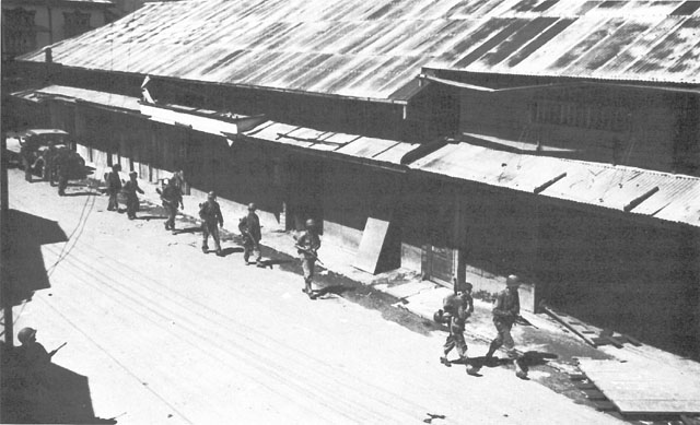 A PATROL FROM THE 7TH CAVALRY moves along Avenida Rizal in Tacloban (above). Flag-waving Filipinos greet the American troops (below).