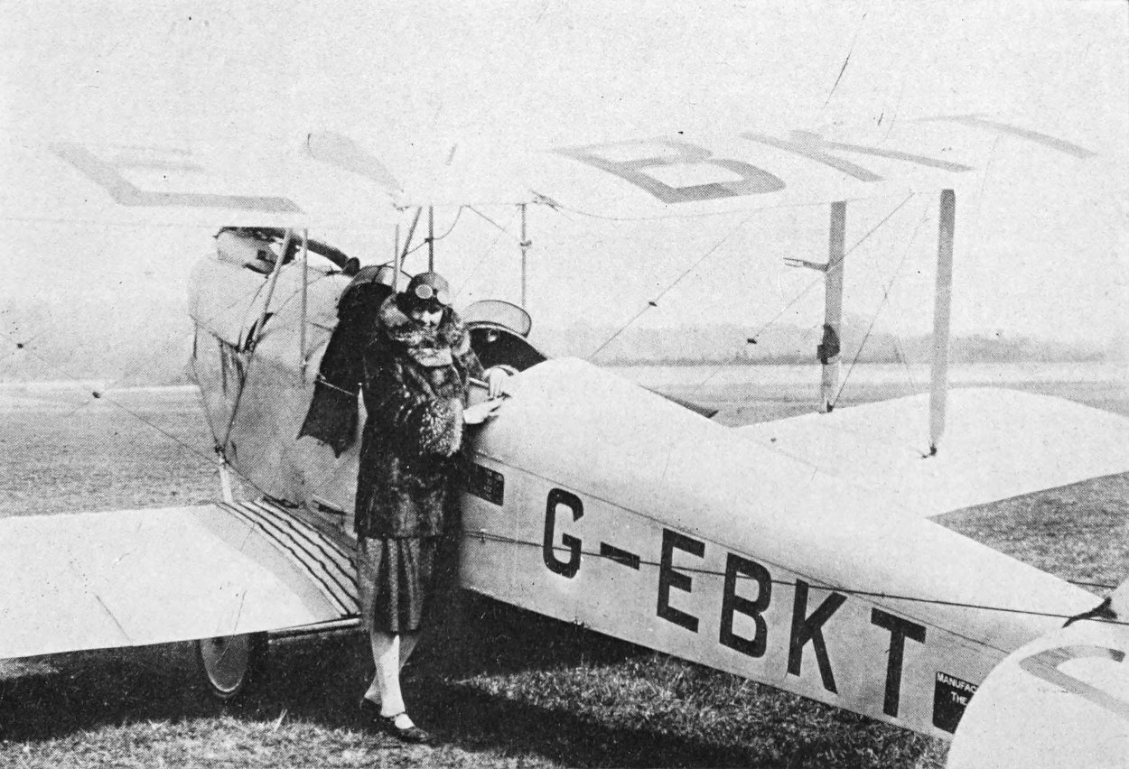 Photo wide outdoor shot of elegantly-dressed woman along side an airplane